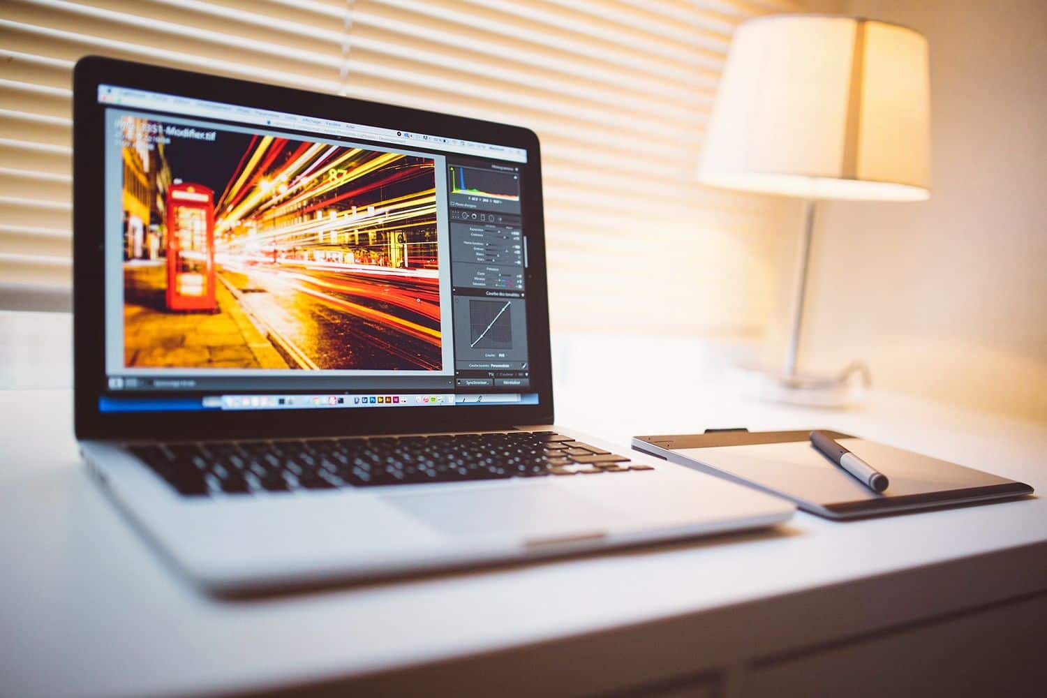 Laptop displaying Lightroom photo editing interface with a vibrant long exposure cityscape image.