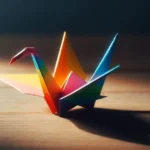 Rainbow-colored origami crane on a wooden surface with dramatic lighting and shadow.