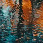 Close-up of water reflecting blue and orange hues with ripples creating an abstract effect.