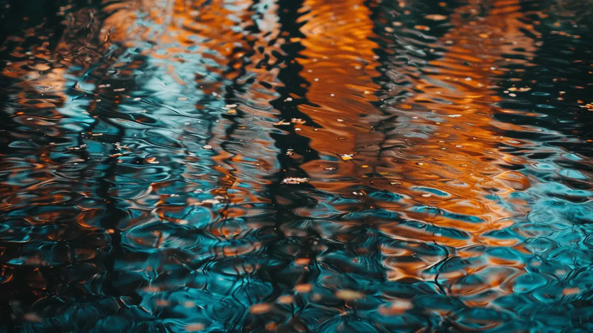 Close-up of water reflecting blue and orange hues with ripples creating an abstract effect.