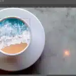 Adobe Photoshop workspace with a Frame Tool active, showing an image of a beach with waves inside a circular frame on a marble background.