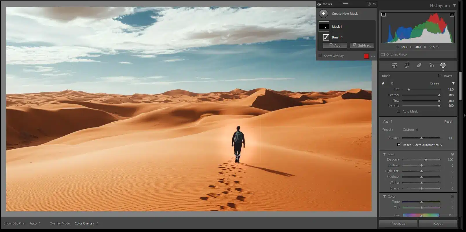 Desert landscape photo with selective adjustments applied using the brush tool to highlight a person walking through sand dunes.