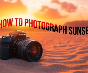 A DSLR camera placed on sandy ground against a vibrant sunset, with the text “How to Photograph Sunsets” floating above