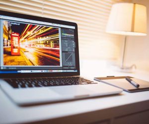 Laptop displaying Lightroom photo editing interface with a vibrant long exposure cityscape image.