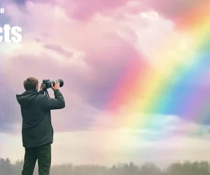 A photographer capturing a vivid rainbow in the sky with a professional camera. The background features soft, colorful clouds with a bright rainbow arching through them, illustrating the use of rainbow photo effects.